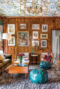 a living room with wood paneling and paintings on the wall, furniture and decor