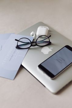 an apple laptop computer sitting on top of a table next to a pair of glasses