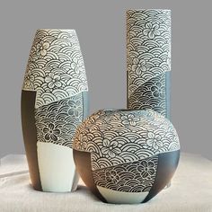 three vases with designs on them sitting next to each other in front of a gray background