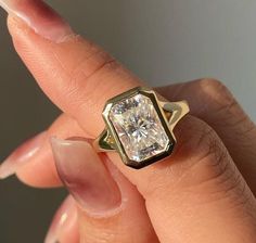 a close up of a person's hand holding a ring with a diamond in it