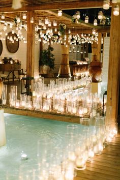 a room filled with lots of candles next to a table full of wine glasses and vases