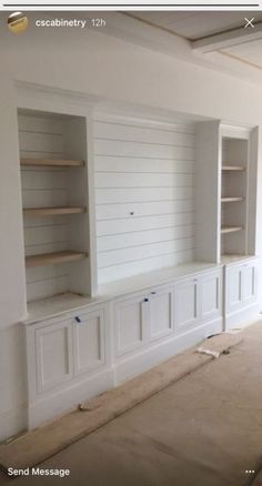 an empty room with built in bookshelves and cabinets