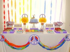 the table is decorated with peace signs, rainbow streamers, and cake on it