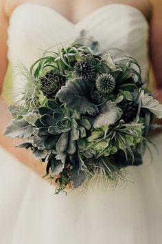 a bridal bouquet with succulents and greenery in the bride's hand