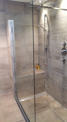 a walk in shower sitting next to a tiled wall with glass doors on both sides