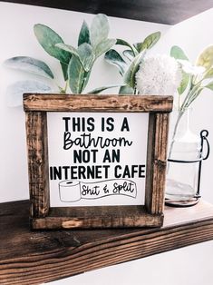 this is a bathroom not an internet cafe sign on a shelf next to a potted plant