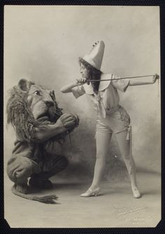 an old photo of a woman dressed as a lion and a man with a hat on his head