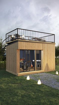 a small wooden building with glass doors on the top floor and balcony above it is surrounded by grass