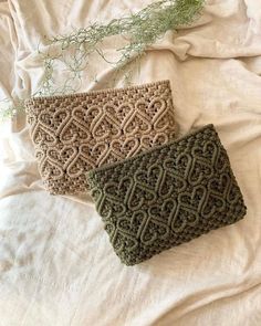 two crocheted purses sitting on top of a white bed next to each other