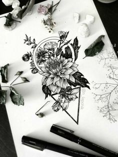 some flowers are sitting on a table next to pens and inking paper with markers