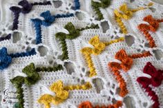 a crocheted blanket with many different colored bows on the edges and in the middle