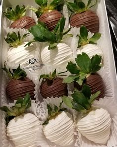 chocolate covered strawberries are arranged in a white box with green leaves on the top