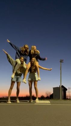 four young women are posing for the camera in front of an empty parking lot at sunset