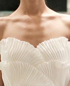 the back of a woman's white dress with pleated details