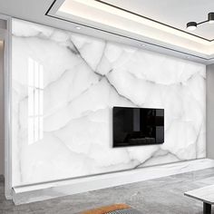 a modern living room with white marble walls and flooring, along with a flat screen tv mounted on the wall