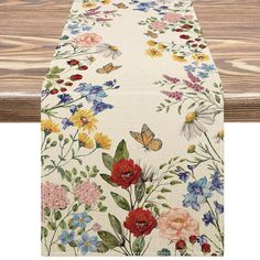 an ironing board covered in flowers and butterflies on a wooden table with wood planks