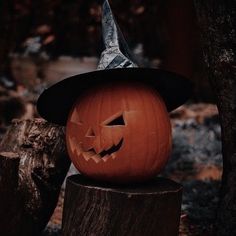 a carved pumpkin with a witches hat on it's head sitting on top of a tree stump