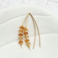 Indulge in luxury with our Wish - Orange Aventurine & Gold earrings. Handcrafted with golden threads and shimmering orange aventurine gemstones, these earrings add a touch of sophistication to any outfit. The perfect accessory to match Pantone's 2024 color of the year, Peach Fuzz. 14k Gold Filled wire Natural Orange Aventurine Gemstones Approximately 1.5" long Includes Silicone Backing Nut Sent in a Ribboned Gift Box with Polishing Cloth Handmade in Montana Gold Aventurine Earrings Gift, Gold Teardrop Earrings With Gemstone Beads, Gold Carnelian Dangle Earrings, Gold Dangle Earrings With Gemstone Beads, Gold Drop Earrings With Natural Stones, Gold Carnelian Earrings With Ear Wire, Carnelian Gold Earrings With Ear Wire, Gold Beaded Earrings With Natural Stones For Gift, Orange Aventurine