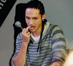 a man with dreadlocks is holding a microphone in his right hand and looking at the camera