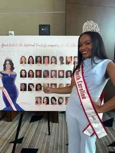 a woman standing in front of a poster wearing a tiara and smiling at the camera