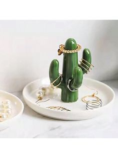 a small green cactus sitting on top of a white plate next to a bowl filled with pearls