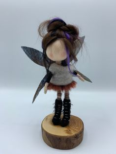 a doll with long hair and boots is standing on a wooden stump holding two scissors