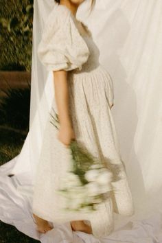 a woman in a white dress holding flowers