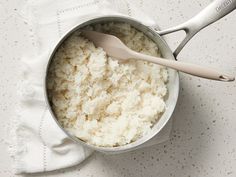 a bowl filled with rice and a spoon on top of a white cloth next to it