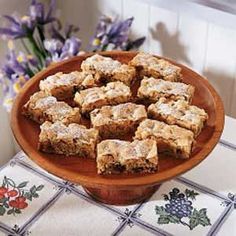 a wooden bowl filled with brownies on top of a table next to purple flowers