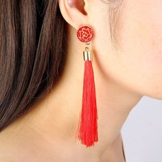 a woman wearing red earrings with tassels