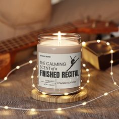 a candle that is sitting on a table next to some string lights and a guitar