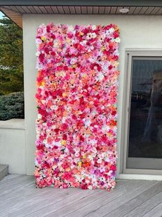 a woman taking a photo in front of a large flowered painting on the side of a building