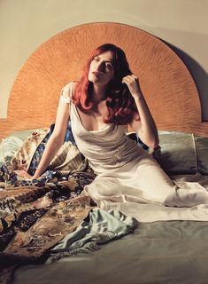 a woman with red hair sitting on a bed