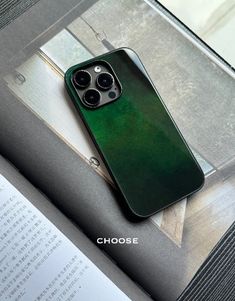 a green iphone case sitting on top of an open book