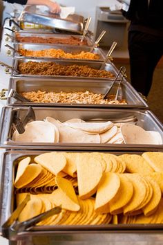 several trays of food are lined up on a buffet table, ready to be served