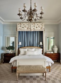 a large bed sitting under a chandelier in a bedroom next to a window