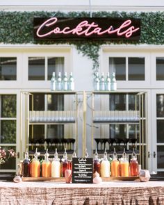 a table topped with lots of bottles of liquid next to a sign that says cocktails