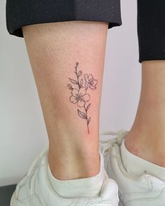 a woman's foot with a small flower tattoo on the left side of her leg