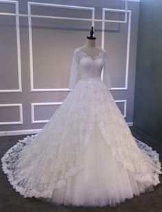 a white wedding dress on display in front of a wall