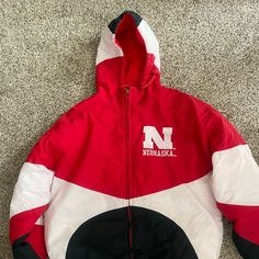 Don’t Miss Out On This Vintage Nebraska Cornhusker Coat, Just Like You Used To Wear On The Playground In The 90s. The Tag Shows That This Is A Men’s Medium And It A Baggy Fit. Please Note That This Vintage Jacket Has Been Well-Loved. The Dangle Part Of The Zipper Has Fallen Off, But The Zipper Is Still Functional Without It. There Is Also A Few Minimal Stains, But Overall This Beauty Is In Great Condition. Husker Fans, This Is Exactly What You Need For Game Day This Season! Collegiate Red Hooded Outerwear, University Red Winter Outerwear For College, Red College Winter Windbreaker, University Red Winter Sports Outerwear, Casual Red Outerwear For Winter Sports, Vintage Crewneck Sweatshirt, Puffy Coat, Nebraska Cornhuskers, Burberry Kids