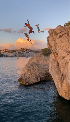 two people jumping off rocks into the water