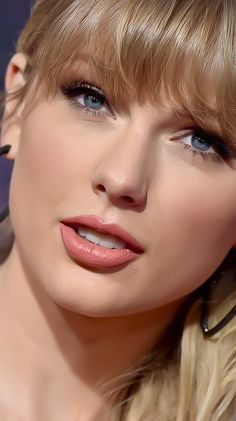 a close up of a woman with blonde hair and blue eyes wearing earrings