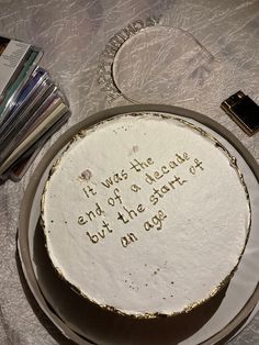 a white cake with writing on it sitting on a table next to cd's