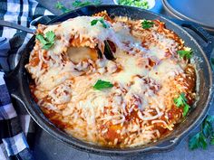 a skillet filled with lasagna covered in cheese and parmesan sauce