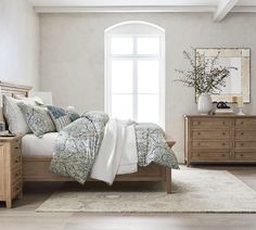 a bedroom with a bed, dresser and mirror on the wall in front of it