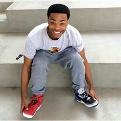 a young man sitting on the steps with his feet up and smiling at the camera