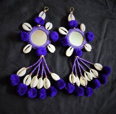 two pairs of purple and white earrings with pom - poms hanging from them