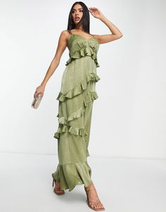 a woman wearing a green dress with ruffles on the bottom and one side