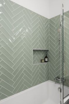 a white bath tub sitting next to a walk in shower under a bathroom wall mounted shelf