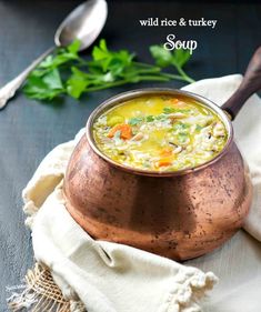 a copper bowl filled with soup on top of a table